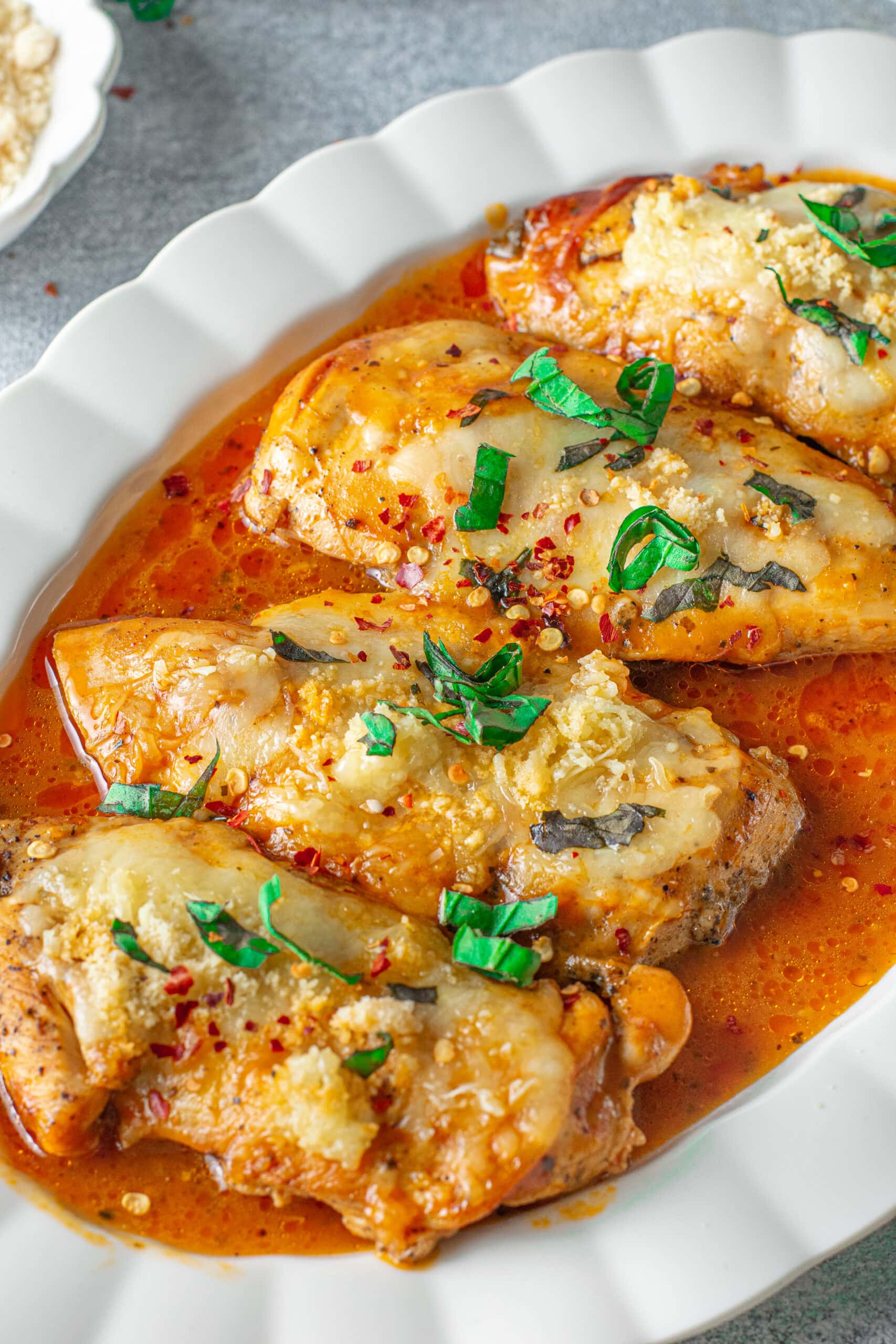 a white platter with instant pot chicken parmesan on top with herbs on top