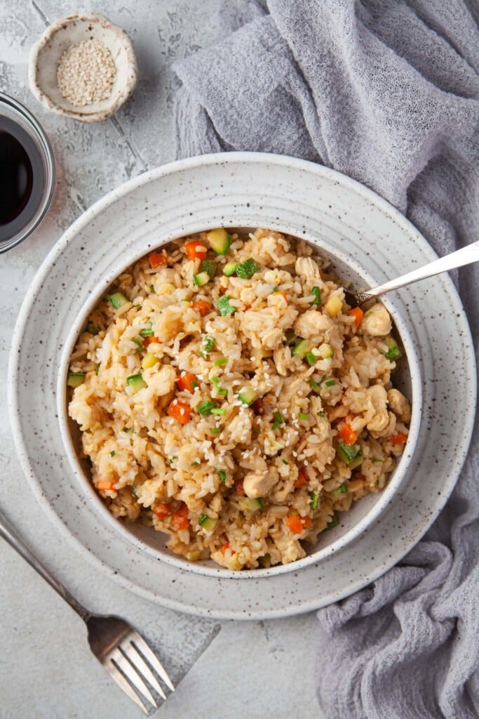 An overhead shot of a bowl of instant pot fried rice with a small bowl of sesame seeds and soy sauce on the side