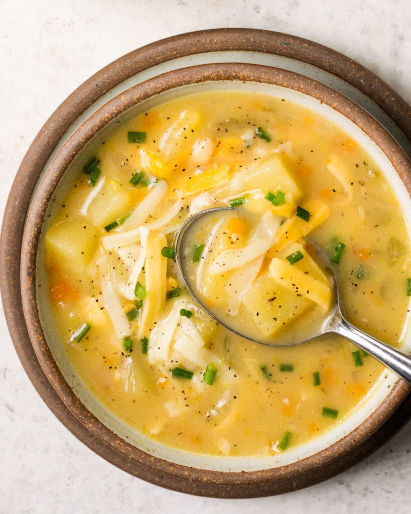 Instant Pot Potato Soup in a brown rimmed bowl with a spoon taking a scoop