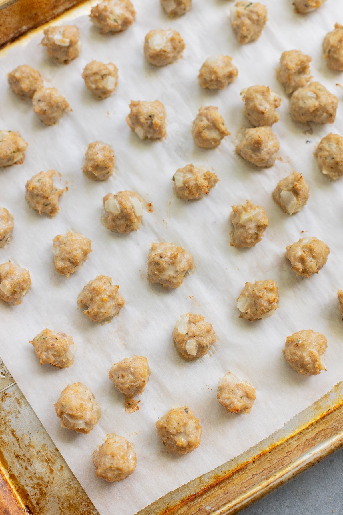 A baking sheet with lots of small meatballs for Italian wedding soup