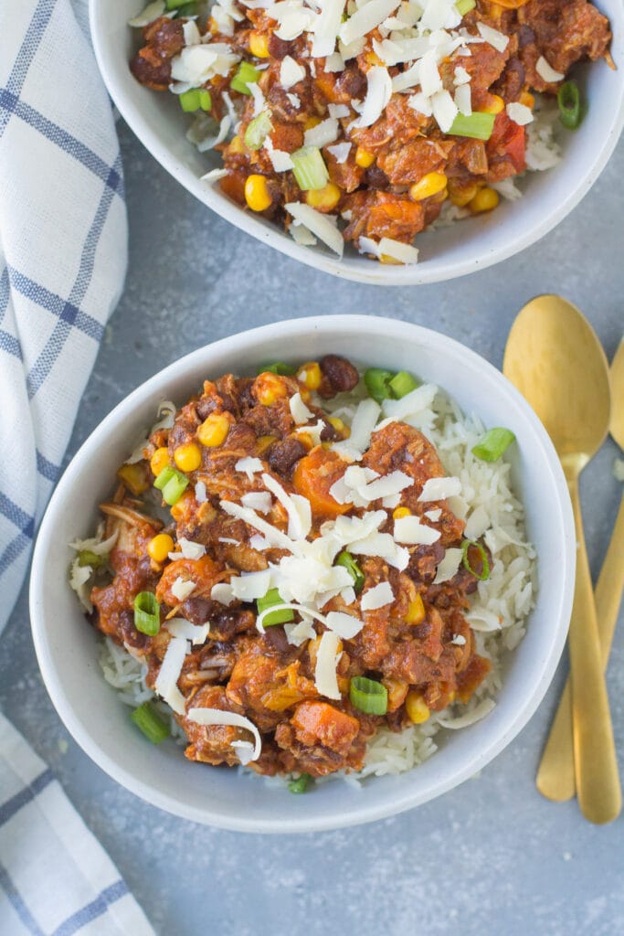 A close up image of Leftover Turkey Chili on a grey background with spoons and linens off to the side