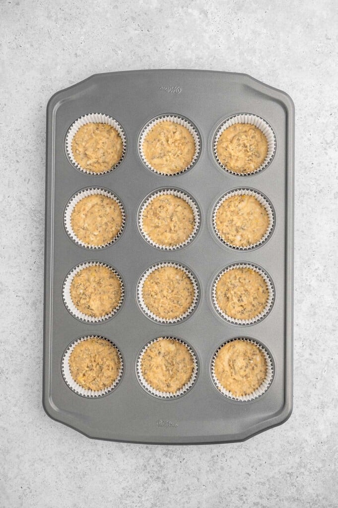 Uncooked lemon chia muffins in a prepared muffin tin.