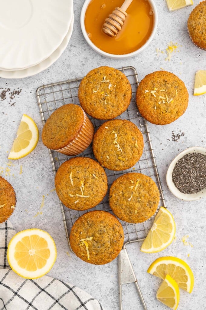 Lemon Chia Muffins on a cooling rack with lemons on the side.