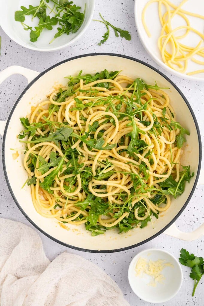 Lemon Pasta in a dutch oven with arugula added in to prep for lemon chicken pasta