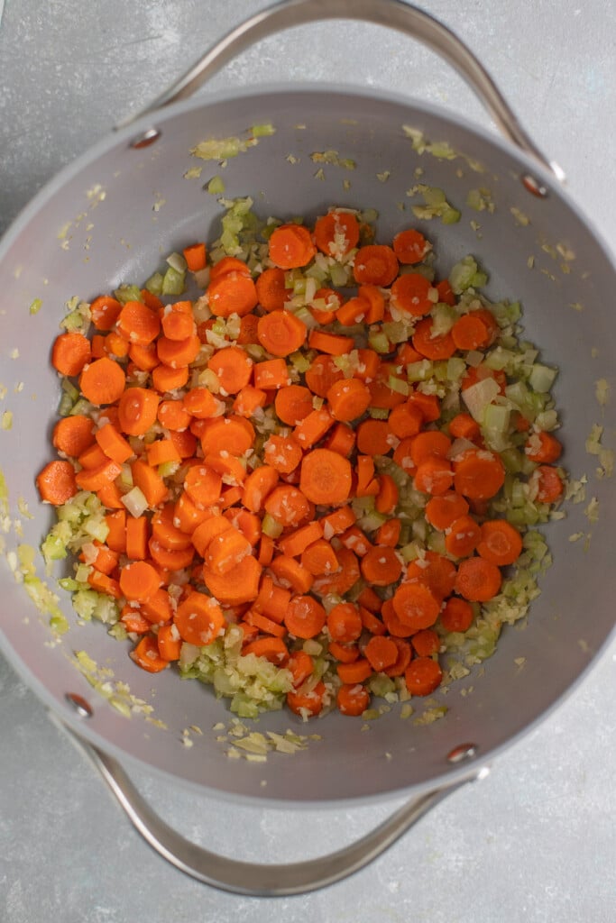 Carrots, celery, onions, and garlic in a pot to make italian meatball soup 