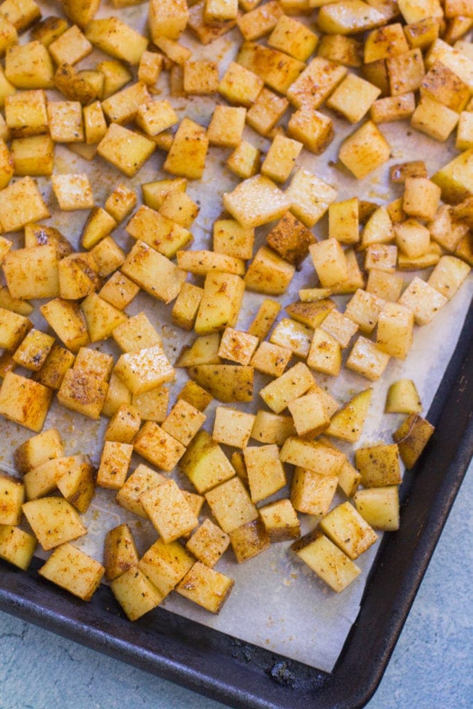 Mexican potatoes on a baking sheet getting ready to go in the oven.