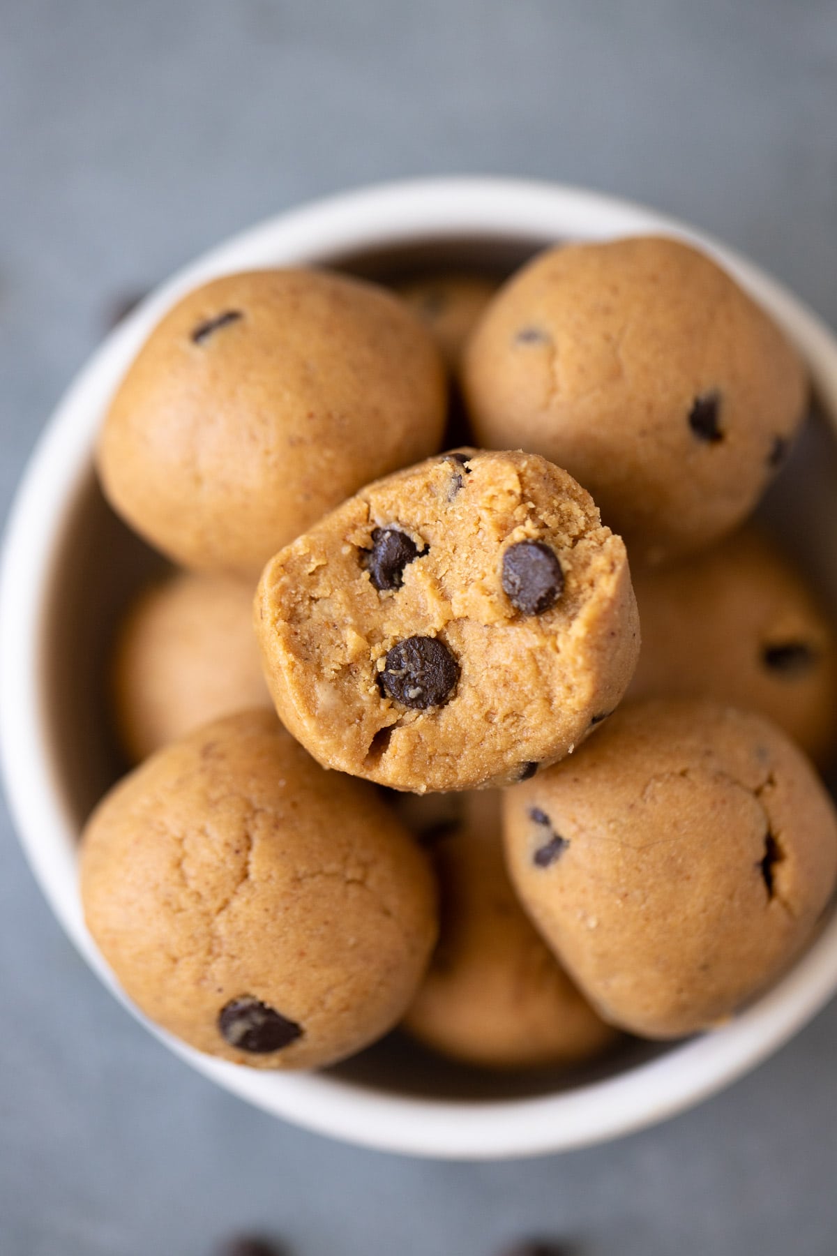 A close up of No Bake Protein Balls Recipe in a small white bowl with a bite being taken out of it