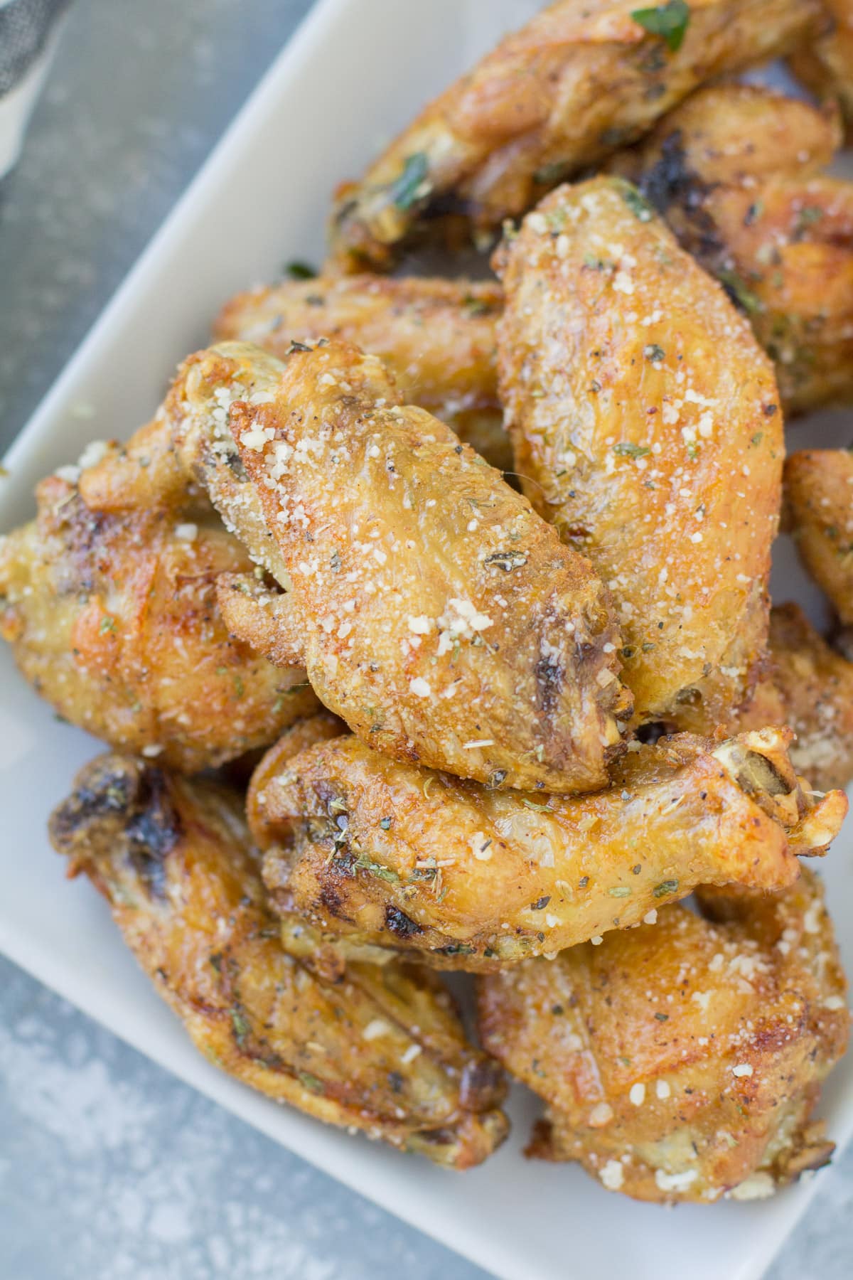 Parmesan Chicken Wings on a white plate on a grey background.
