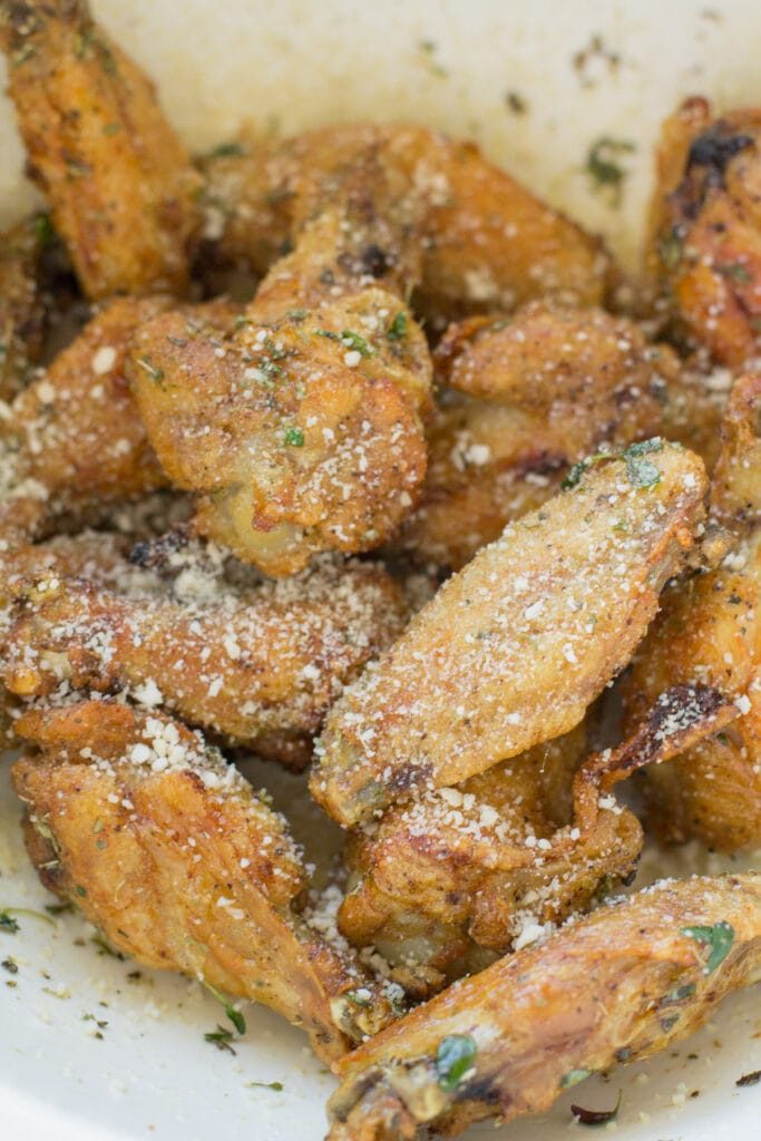 Garlic Parmesan Chicken Wings in a white bowl being tossed