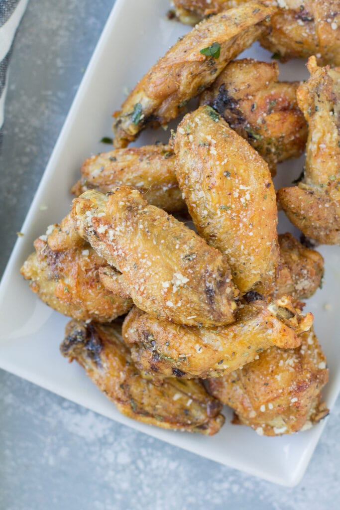 Cheesy Chicken Wings on a white plate on a grey background