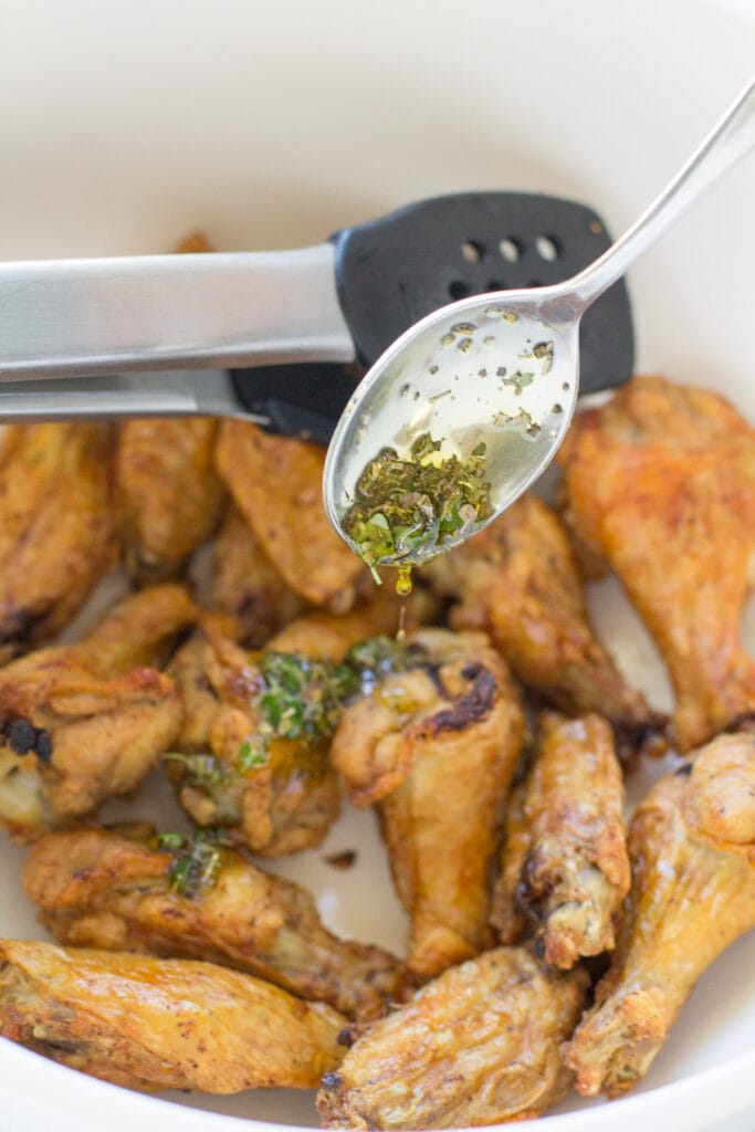 Crispy Parmesan Chicken Wings being tossed in a bowl