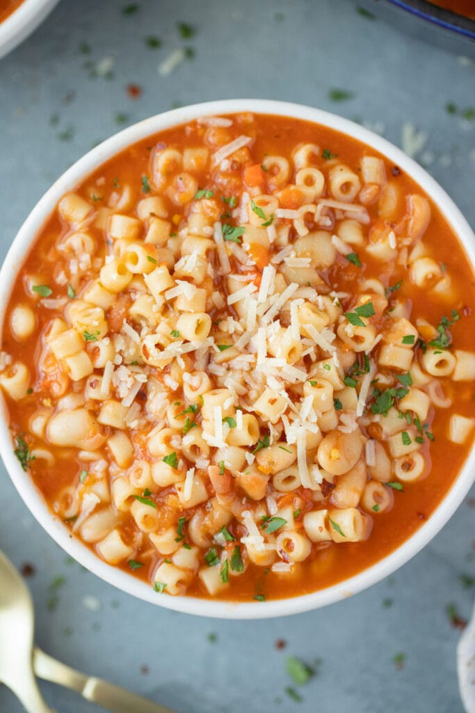 A close up of pasta fagioli soup in a white bowl on a grey background