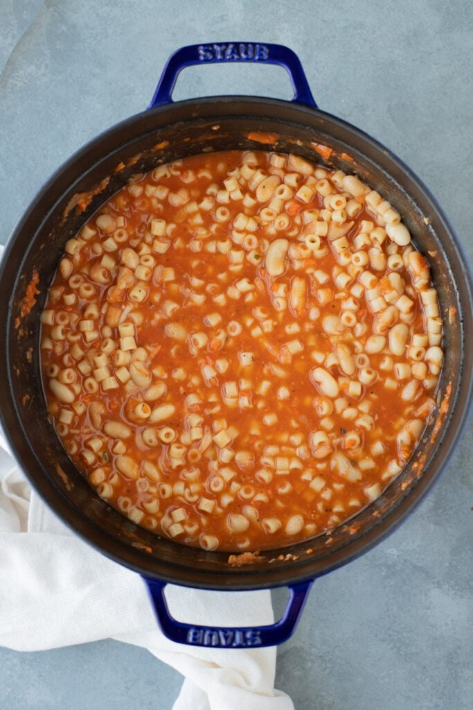 beans and pasta being added into a pot of pasta fagioli