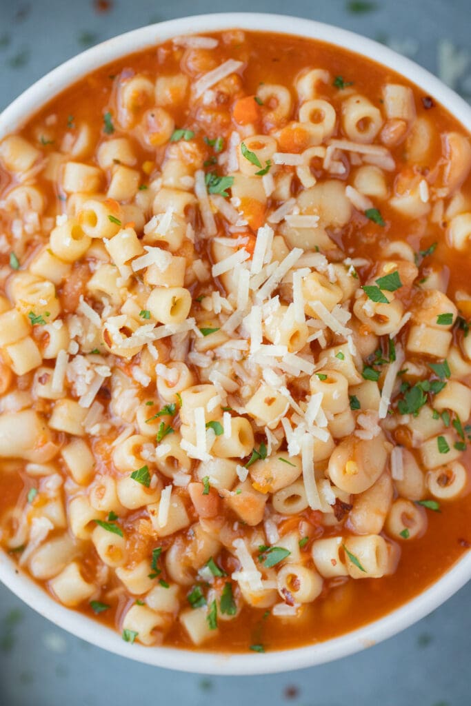 A close up overhead shot of pasta fagioli soup with cheese on top