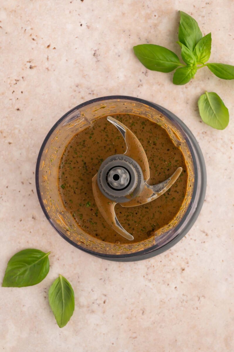 Homemade Balsamic dressing in a small food processor with fresh basil on the side.