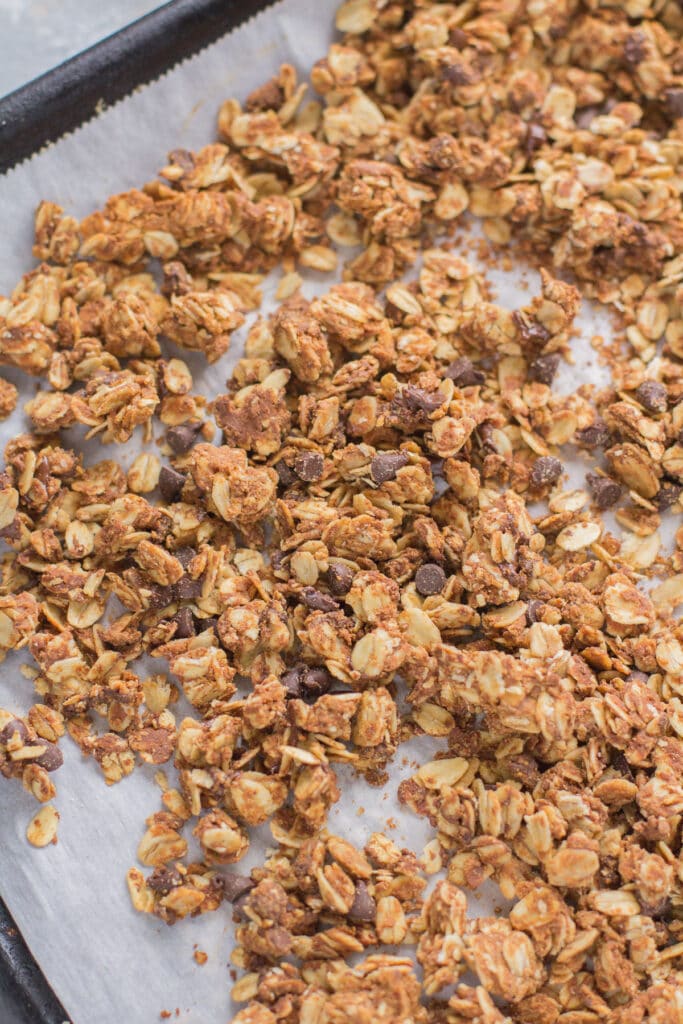 An overhead shot of peanut butter granola on a parchment lined baking sheet.