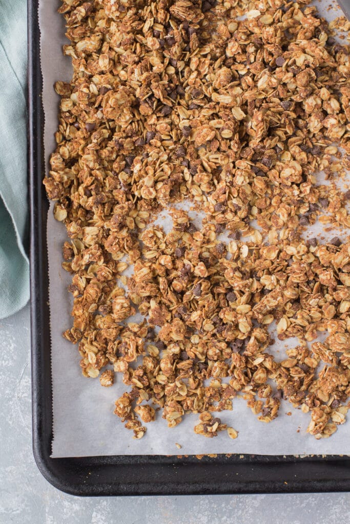 Peanut Butter Granola freshly baked out of the oven on a parchment lined baking sheet