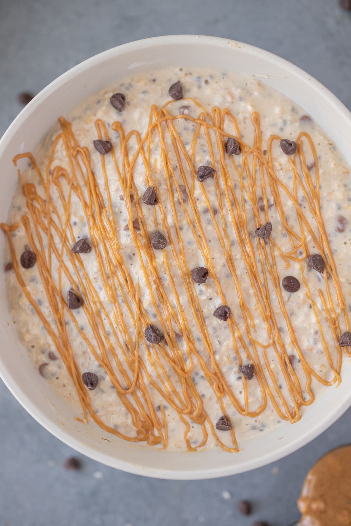 A close up of peanut butter overnight oats with chocolate chips and peanut butter drizzle on top