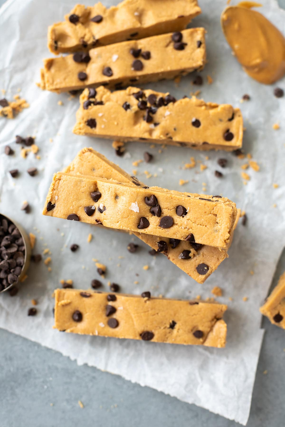 Homemade Peanut Butter Protein Bars on a piece of parchment paper with peanut butter and chocolate off to the side