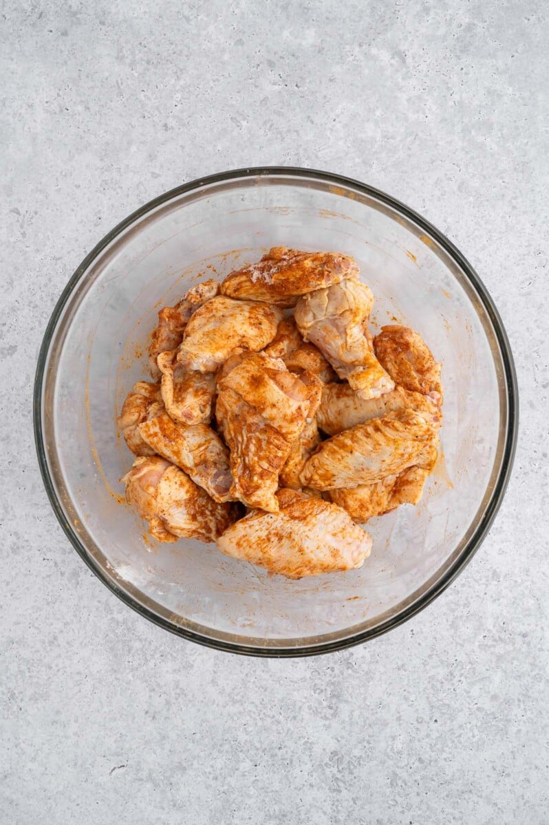 Chicken wings in a bowl tossed in seasonings to make pickle chicken wings.