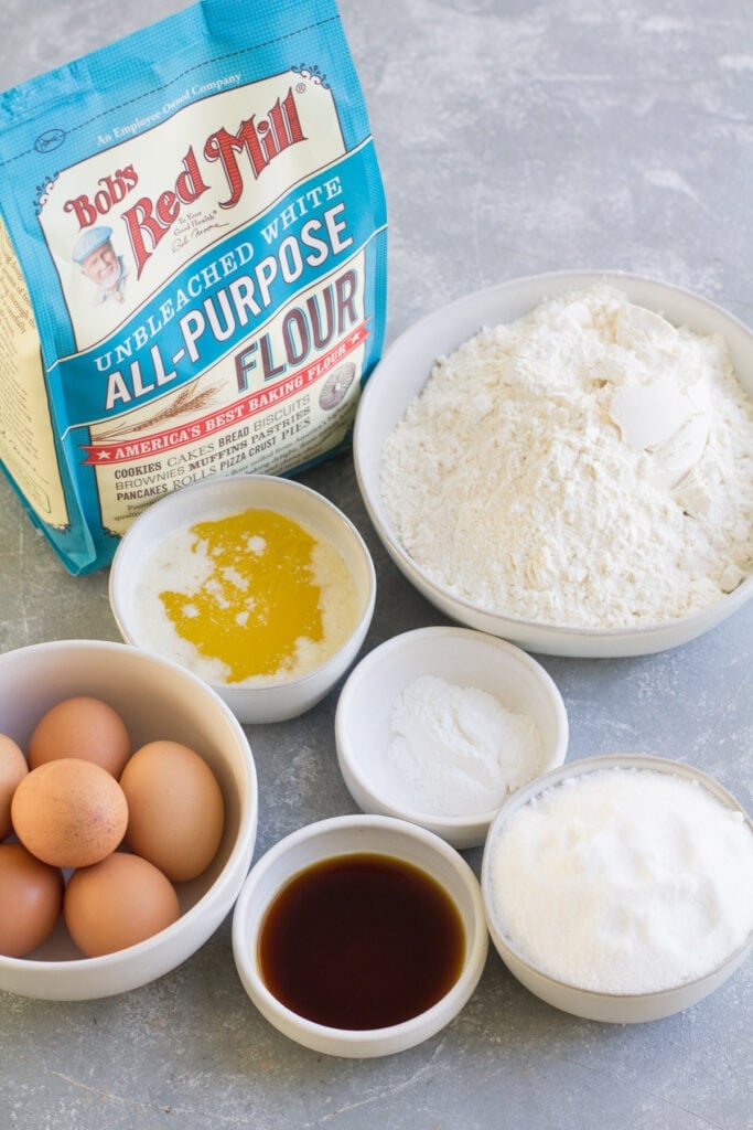 Ingredients for Pizzelle Cookies in small white bowls on a grey background
