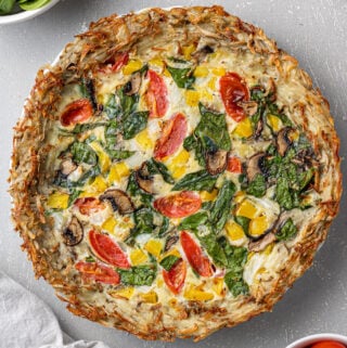 An overhead image of Potato Crust Quiche on a grey background with a white linen