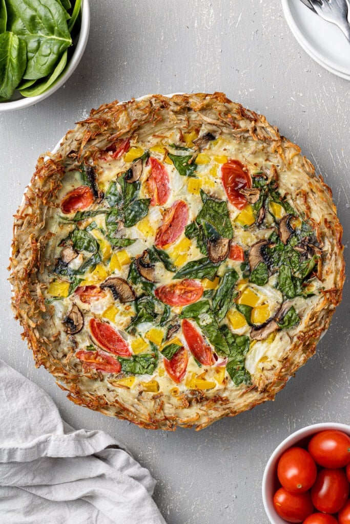 An overhead image of Potato Crust Quiche on a grey background with a white linen