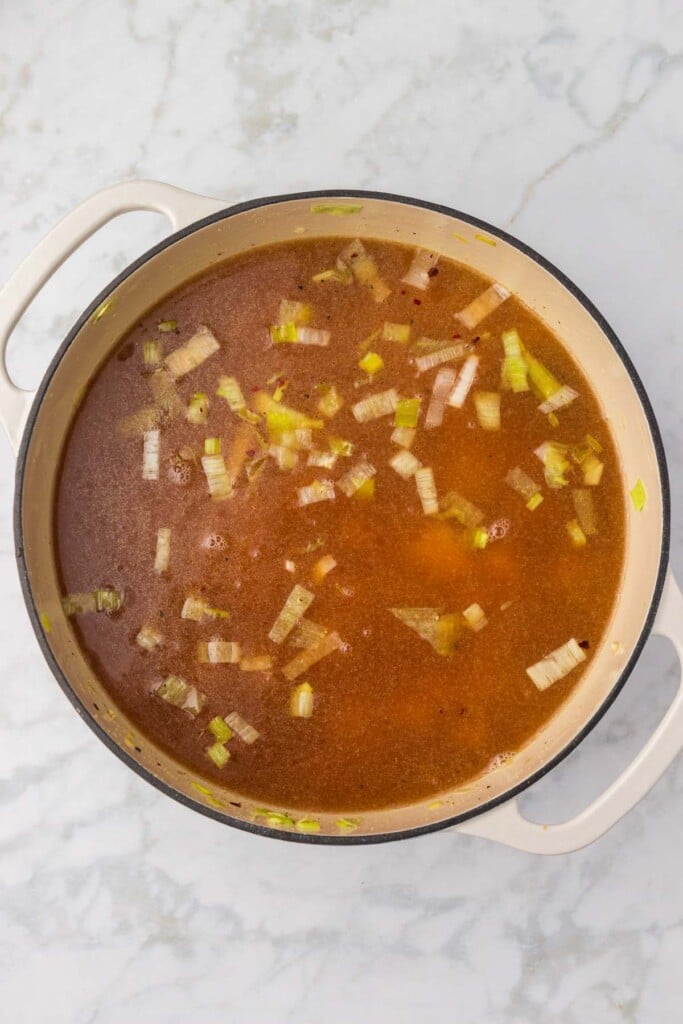 Uncooked potato leek soup in a dutch oven on a grey background.