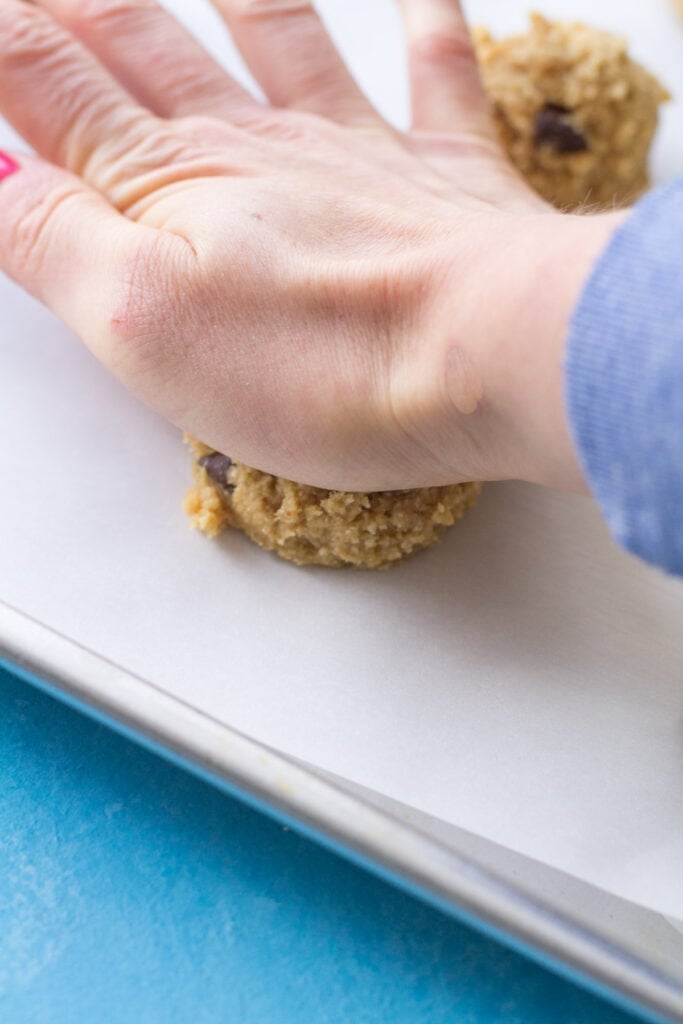 a hand pressing down protein cookie dough batter