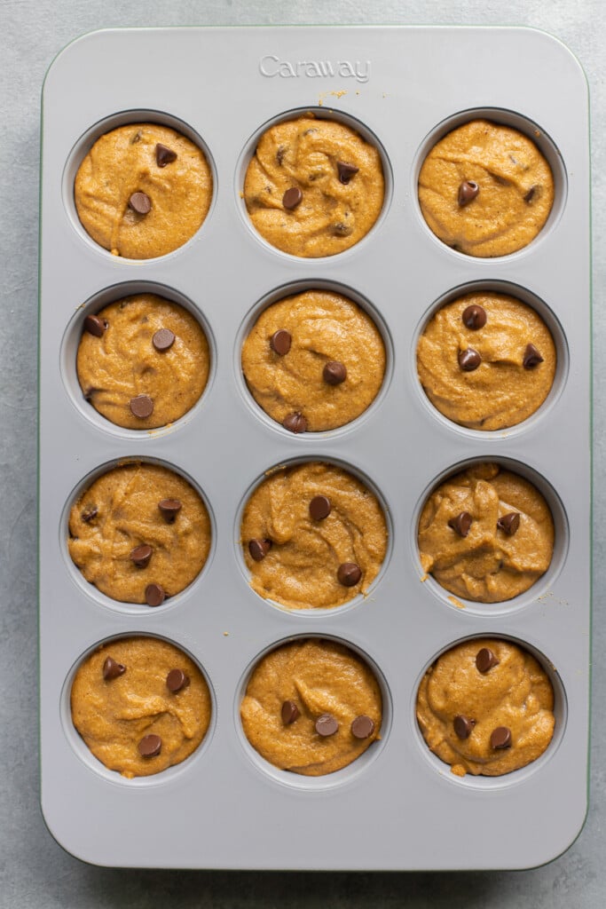 A grey muffing tin filled with healthy pumpkin muffins before being baked