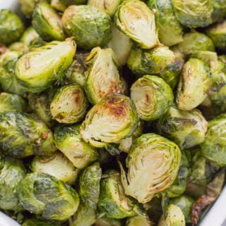 A white serving dish filed to the top with garlic roasted brussels sprouts.