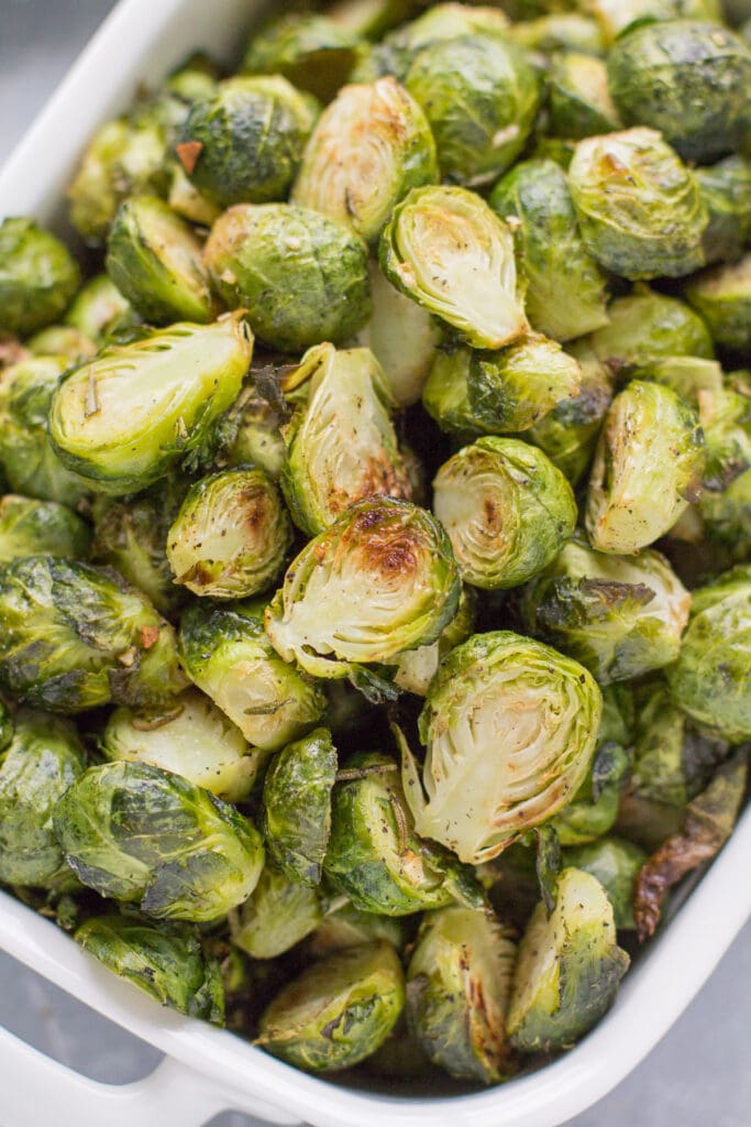 A white serving dish filed to the top with garlic roasted brussels sprouts.