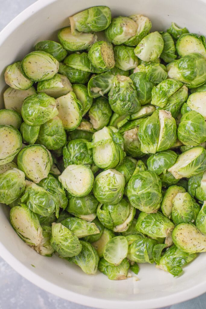 roasted brussels sprouts in a bowl being mixed together to be roasted
