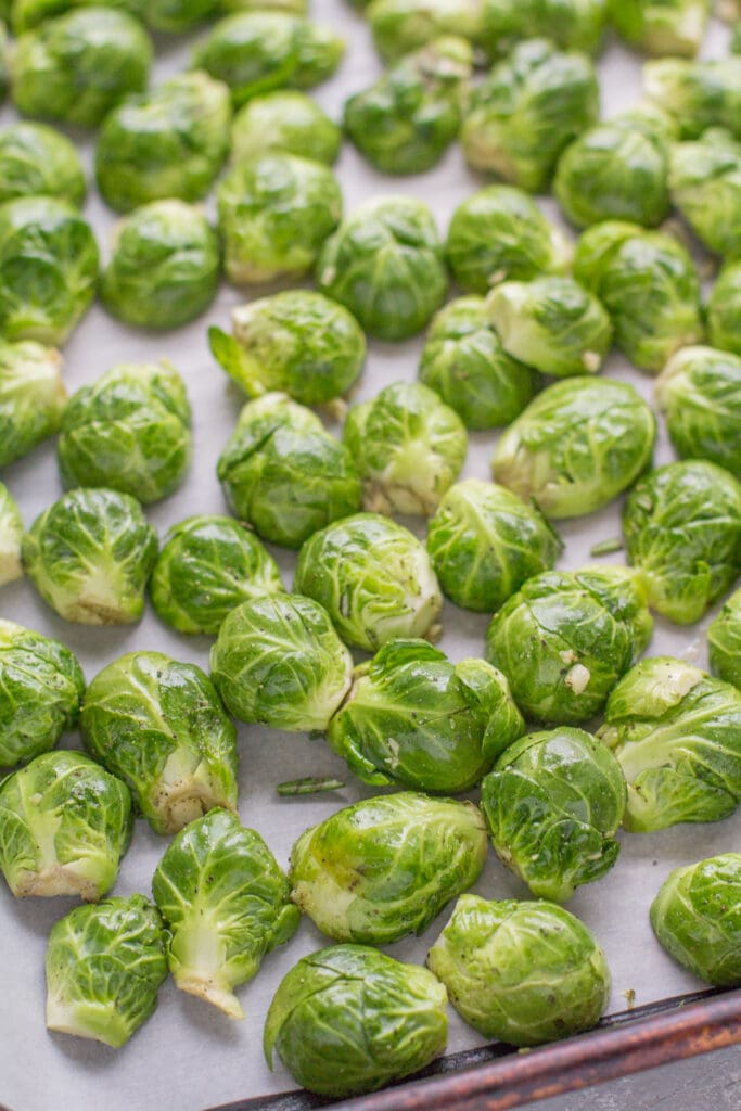 roasted brussels sprouts on a parchment lined sheet pan going into the oven
