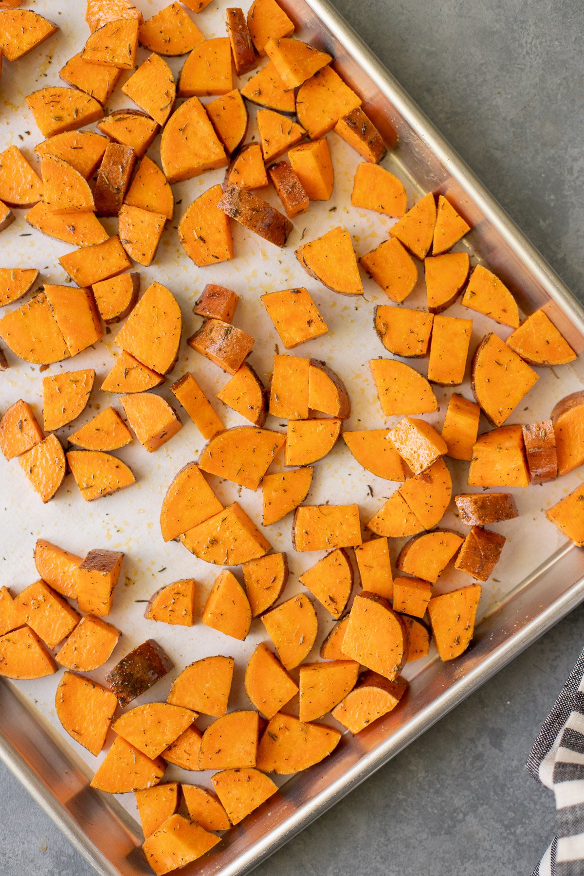 Cubed sweet potatoes on a parchment lined baking sheet before baking
