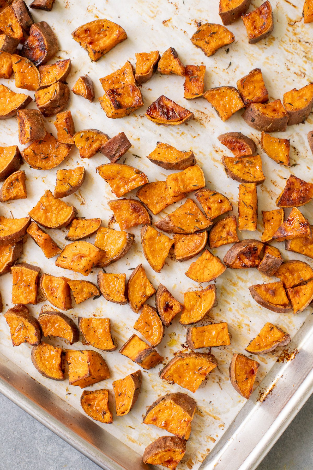 Crispy roasted sweet potatoes on a parchment paper lined baking sheet