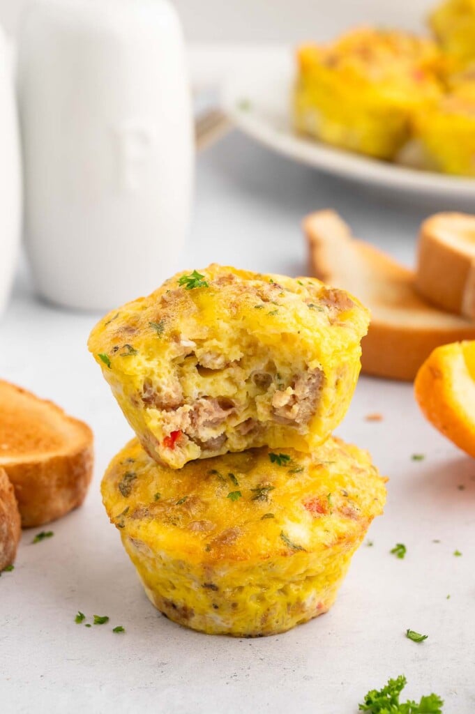 Two sausage egg muffins stacked on top of each other (the top has a bite taken out of it).