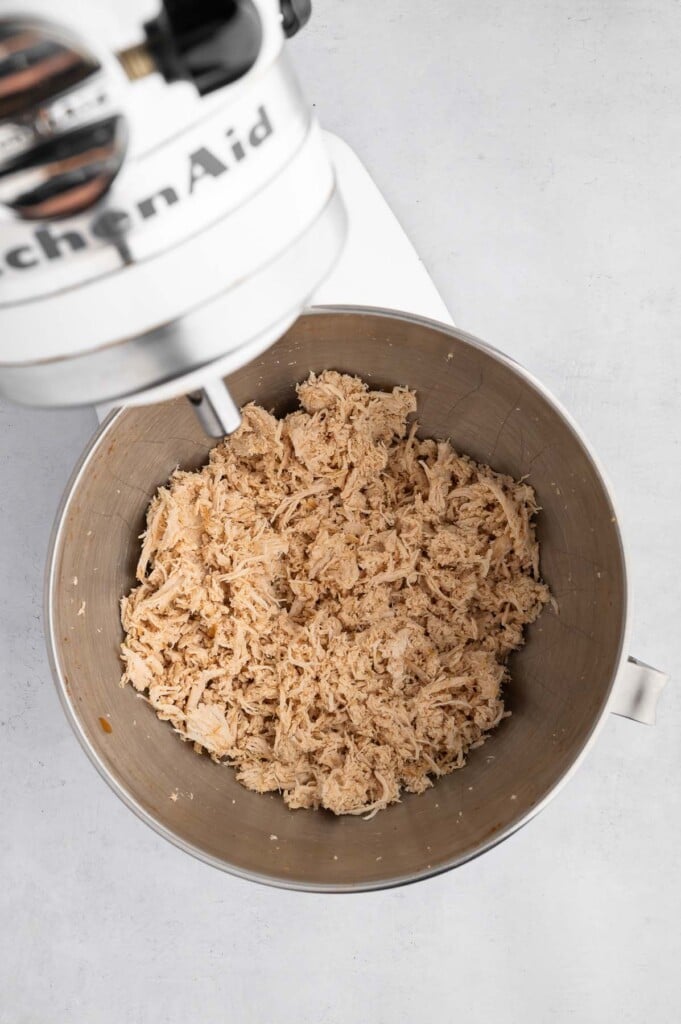 Shredded chicken in a kitchen aid mixer bowl.