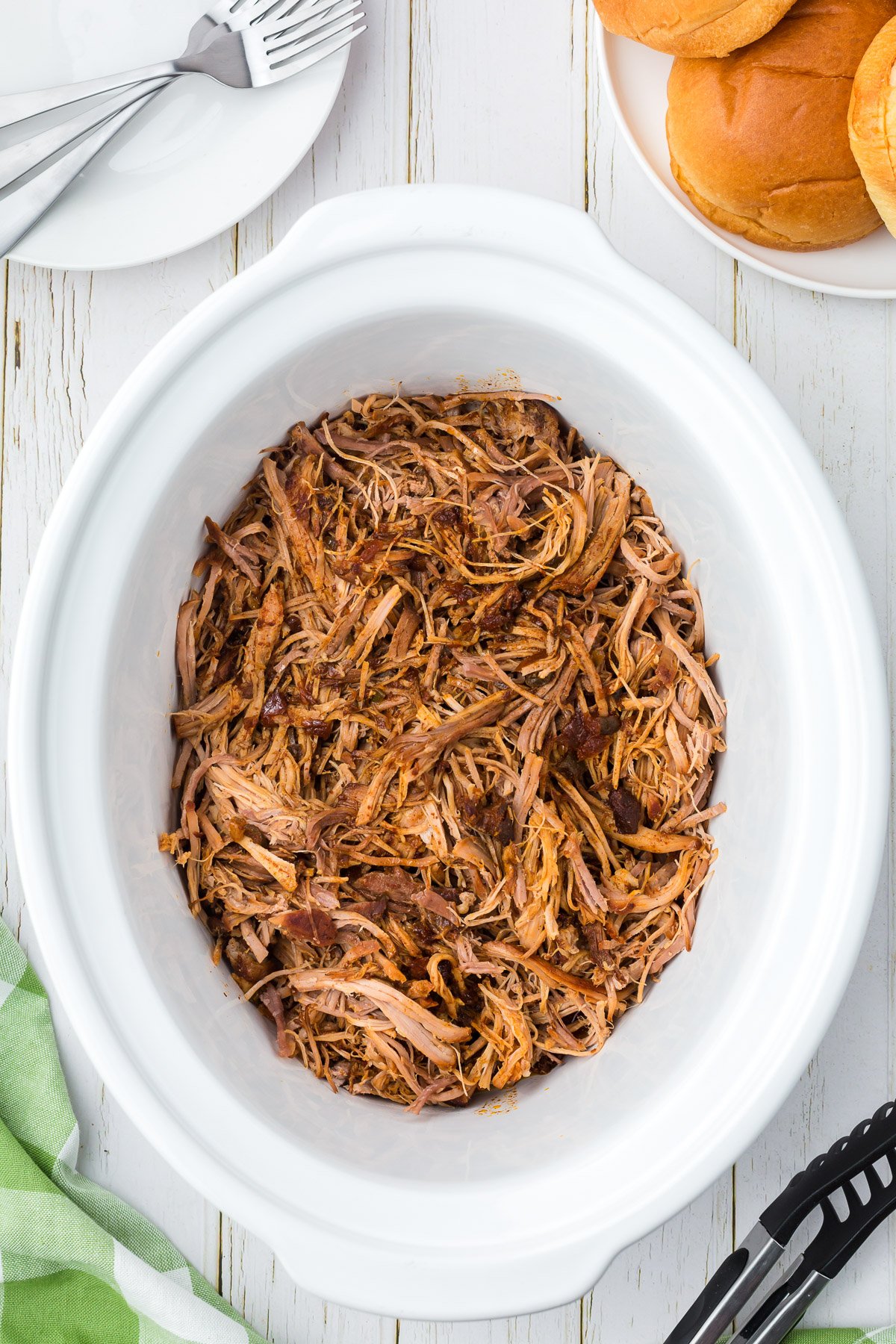 pulled pork after being cooked and shredded in a white crockpot 