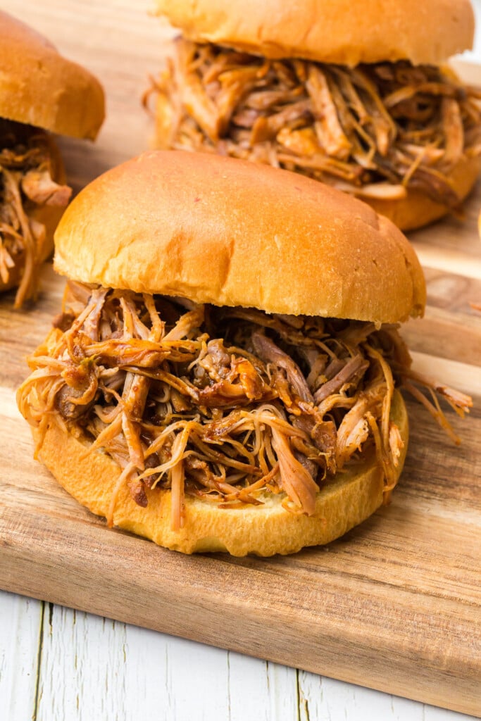 slow cooker pulled pork sandwich on a wooden platter