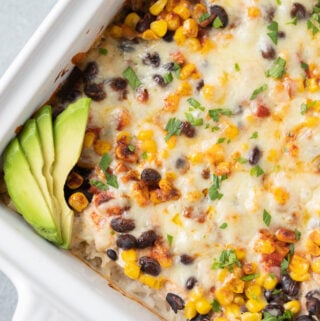 A close up of Southwest Chicken Casserole in a white baking dish on a grey background