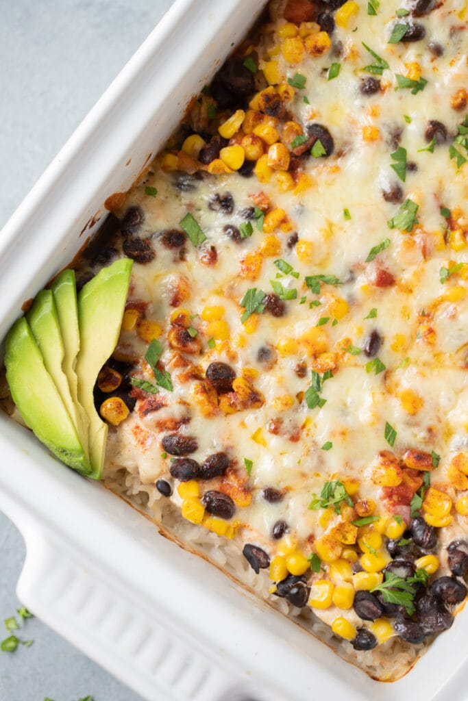A close up of Southwest Chicken Casserole in a white baking dish on a grey background