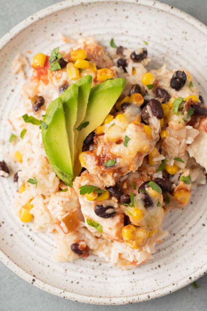 A close up of Cheesy Southwest Chicken and Rice Casserole on a white plate on a grey background