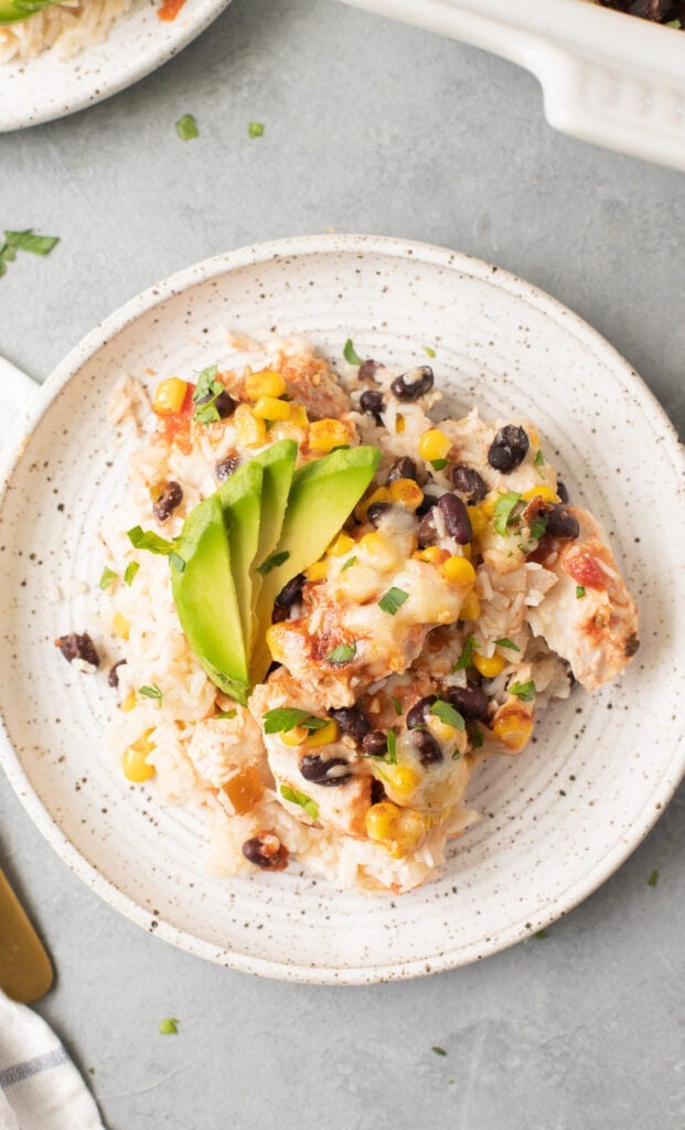 A close up of Cheesy Southwest Chicken and Rice Casserole on a white plate on a grey background
