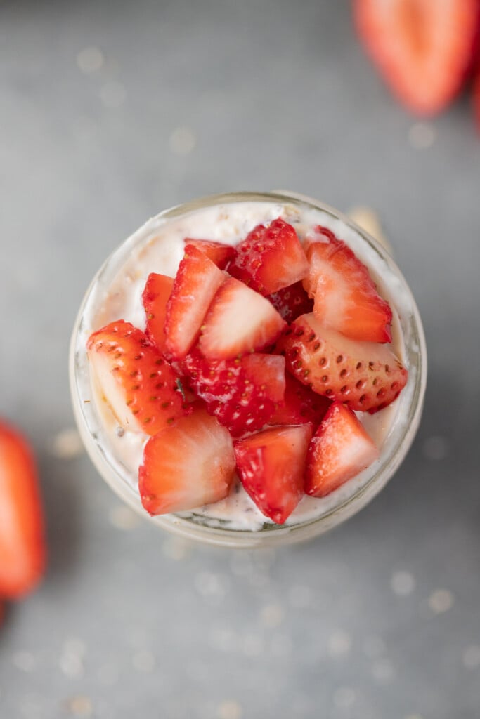 An overhead image of strawberry overnight oats on top of a grey background