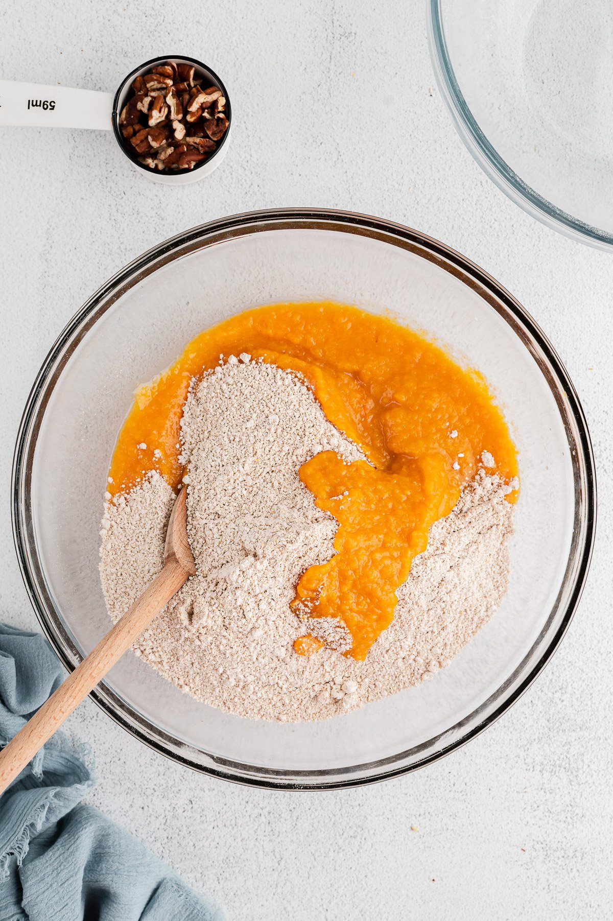 Dry ingredients being added to the sweet potatoes puree in a white bowl for sweet potato muffins