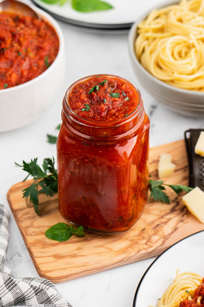 a mason jar of healthy turkey bolognese with a bowl of pasta and sauce in the background