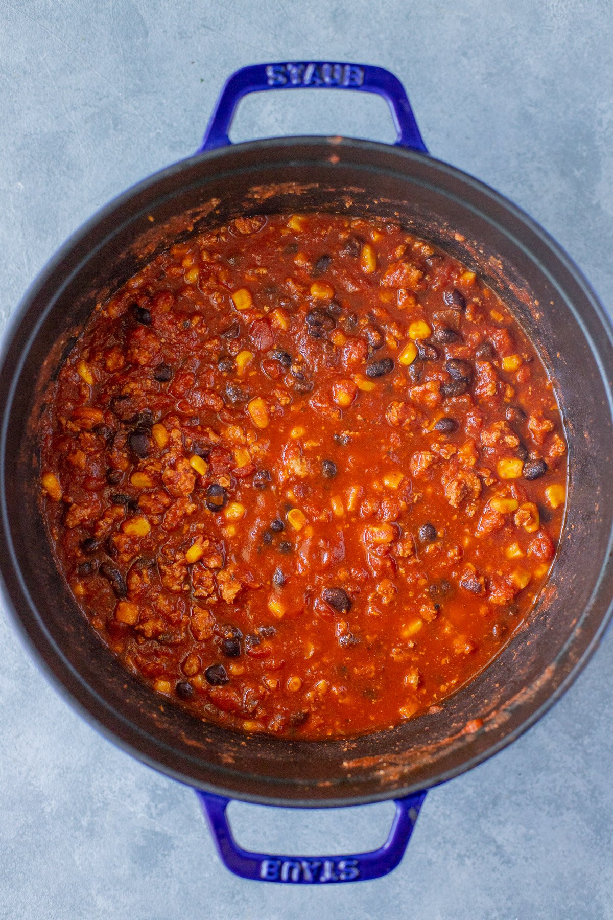 A pot of ground turkey chili on a blue background