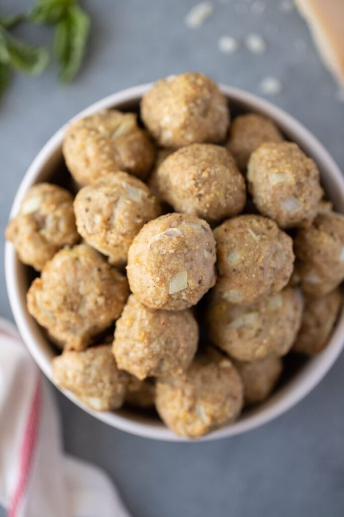 a white bowl filled with healthy turkey meatballs on a grey background