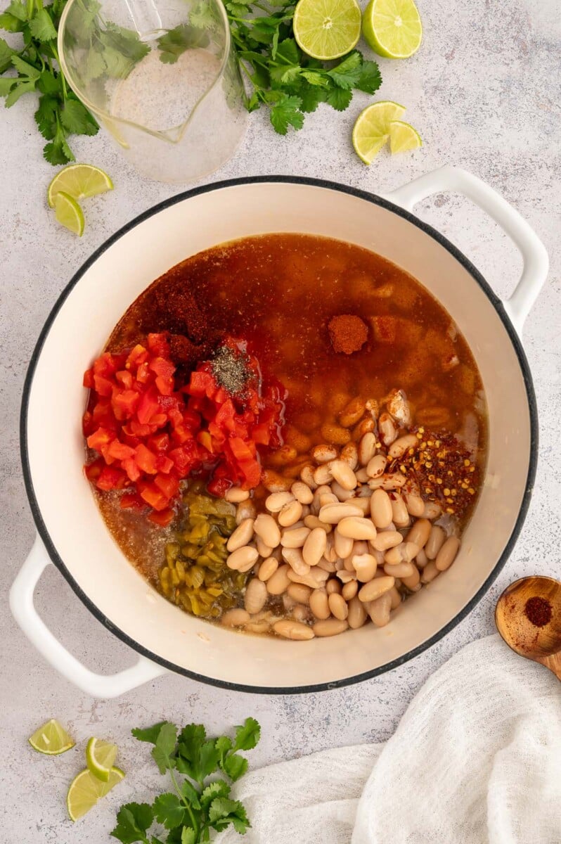 Most of the ingredients for white bean chicken chili in a dutch oven before cooking and stirring together. 